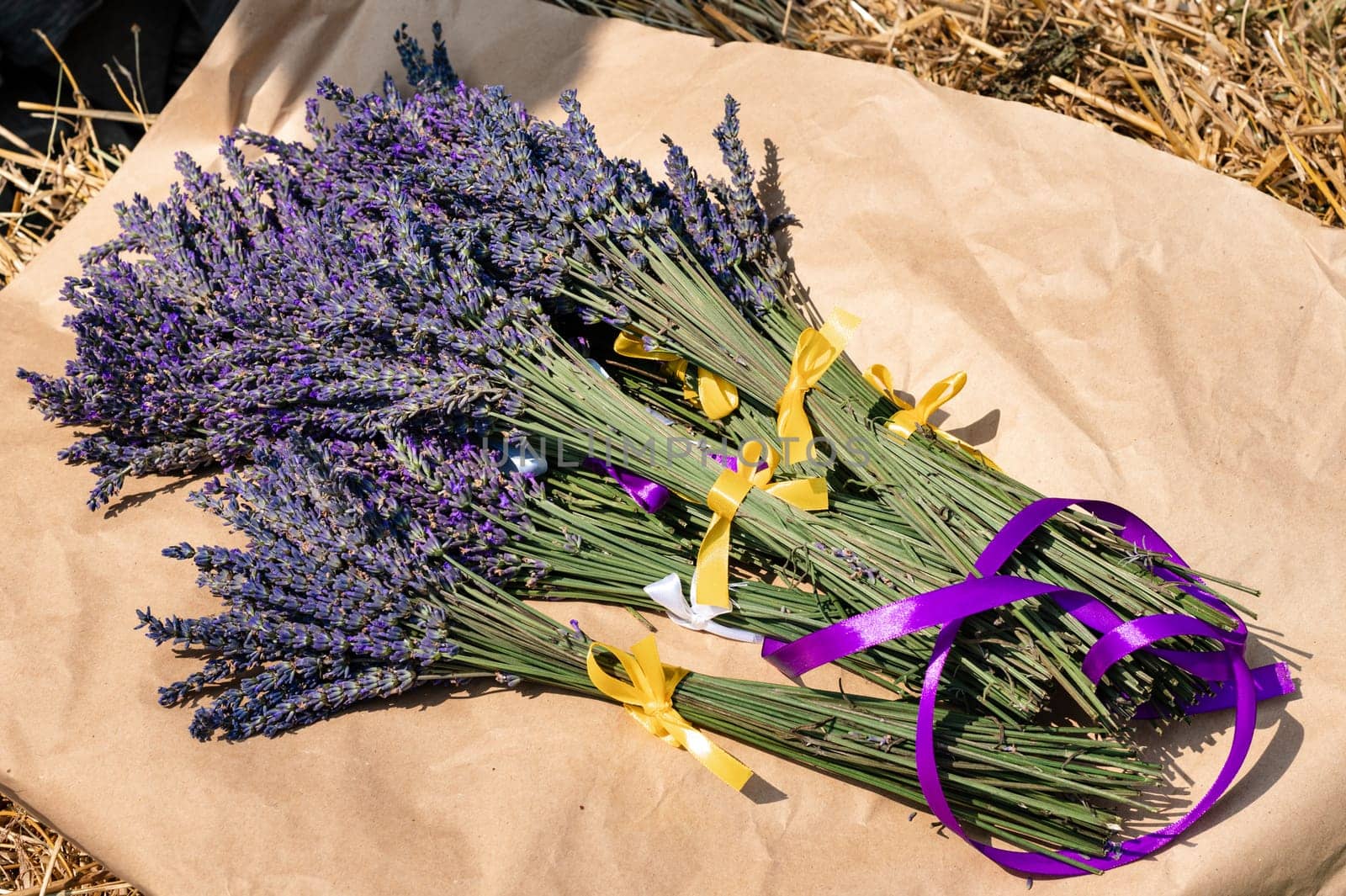 Lavender bouquets with purple and yellow ribbons lie on kraft paper