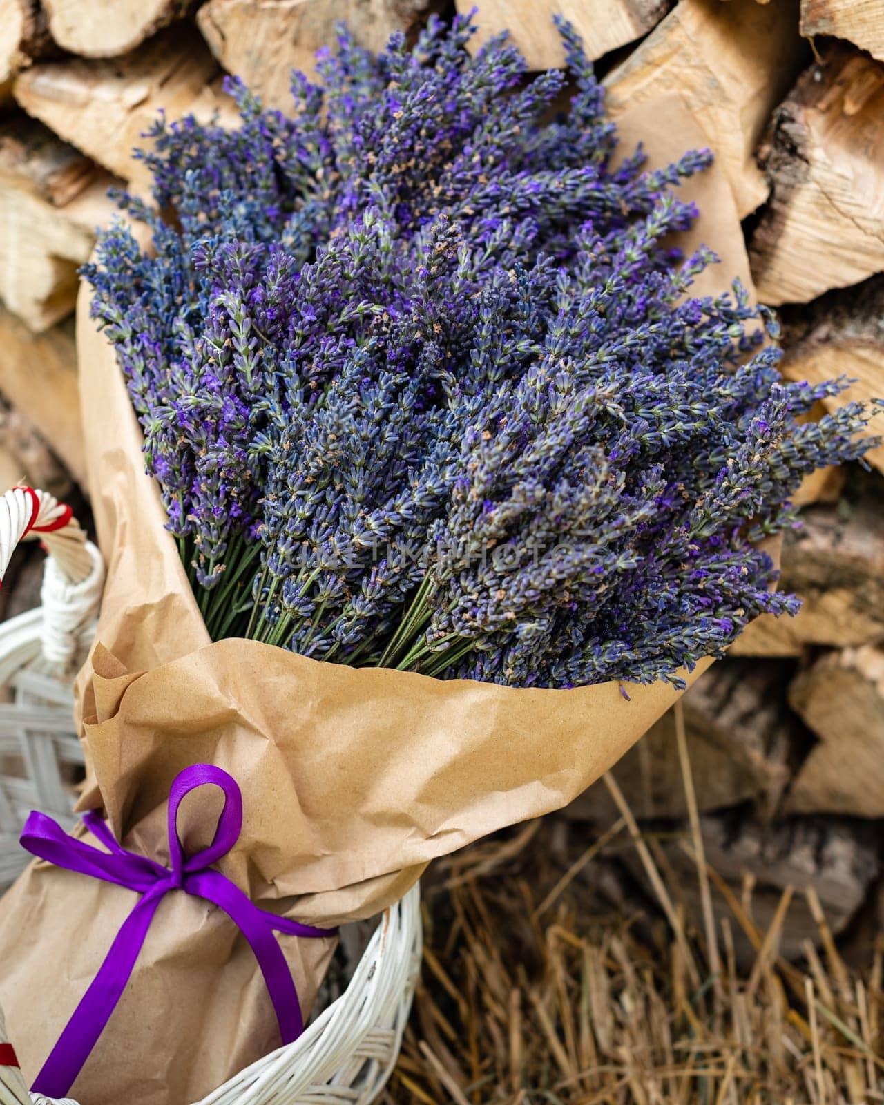 A lush and large bouquet of lavender wrapped in paper on a background of firewood by Niko_Cingaryuk