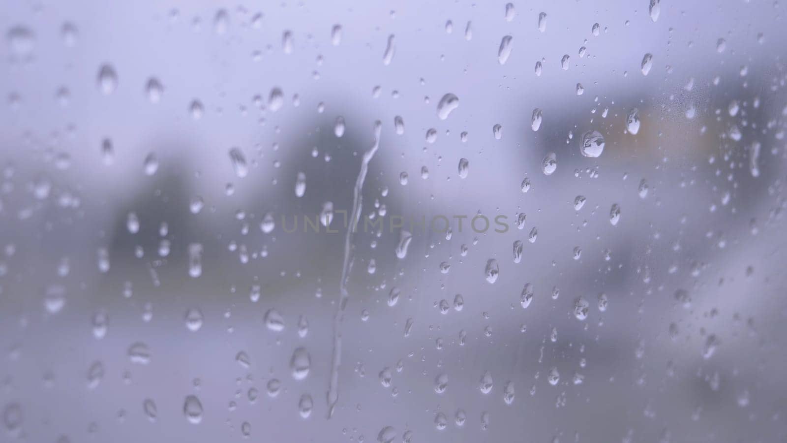 Glass wet, rain drops on the drenched window glass, autumnal rainy landscape blurred. Raindrops on the window from rain.