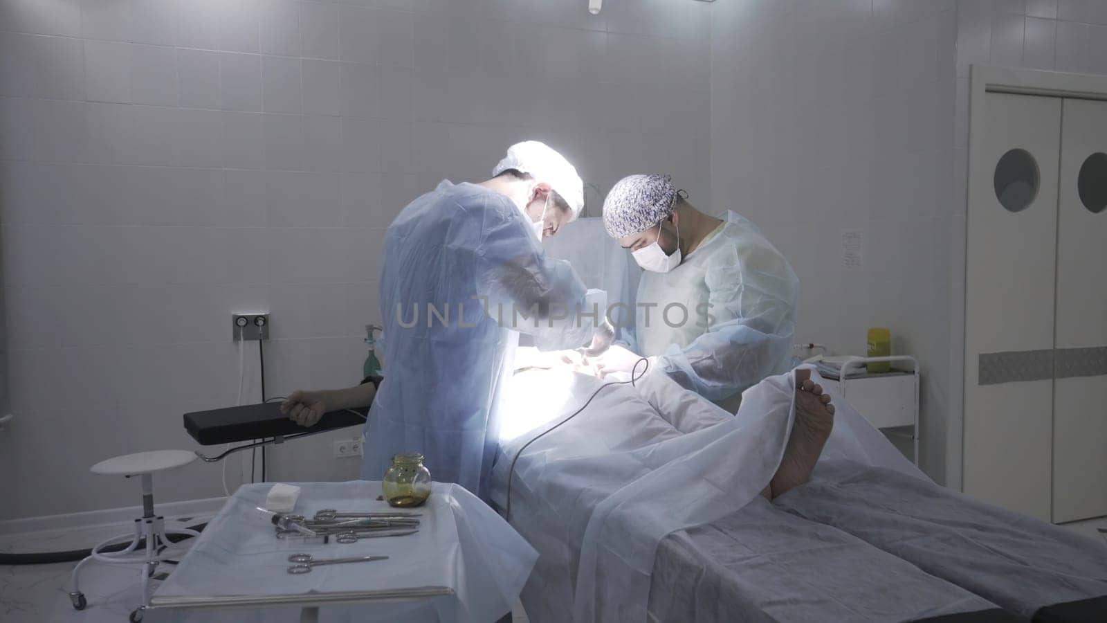 Two professoinal surgeons performing phimosis surgery. Male health concepts, medical procedure on male penis in sterile operating room.