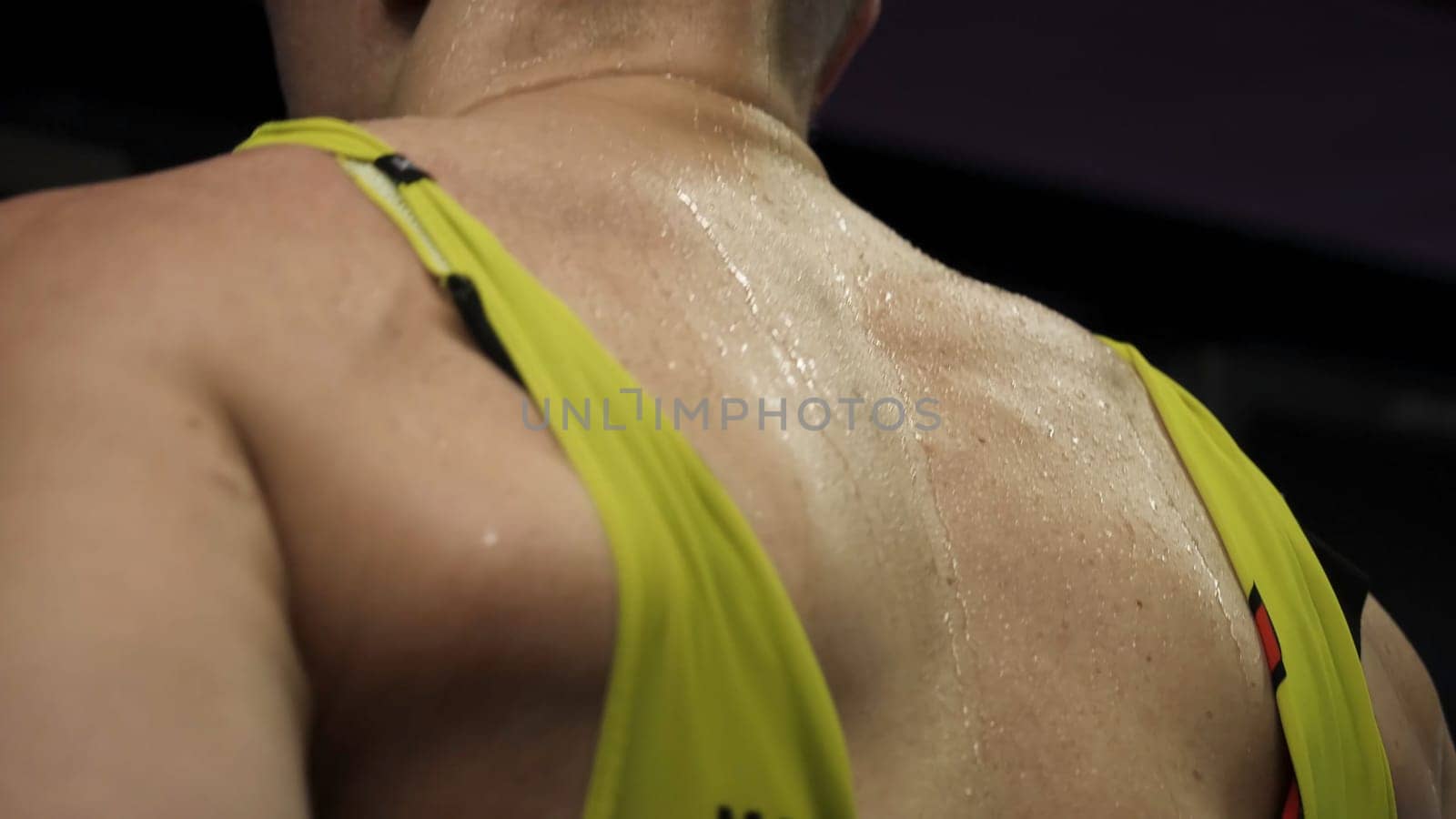 Athlete running on race track. Wet back of athlete running on a treadmill in gym.