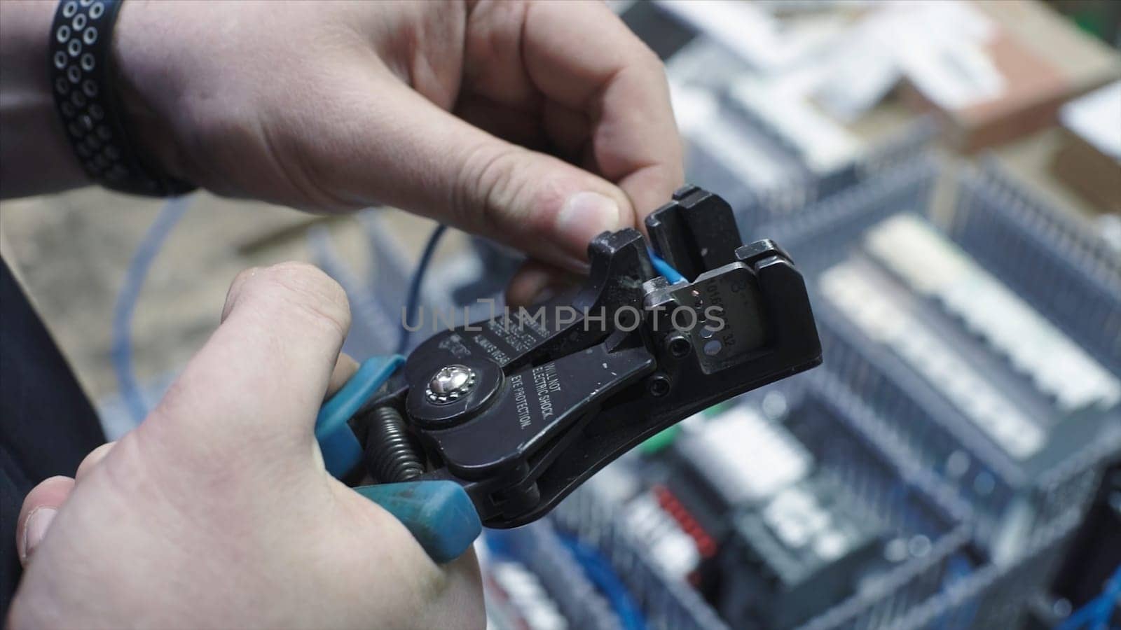 Man cutting off electrical wire with tool. Clip. Electrician with his bare hands cuts off part of electrical wire. Electrician cuts off the surface of electrical wire with special tool.