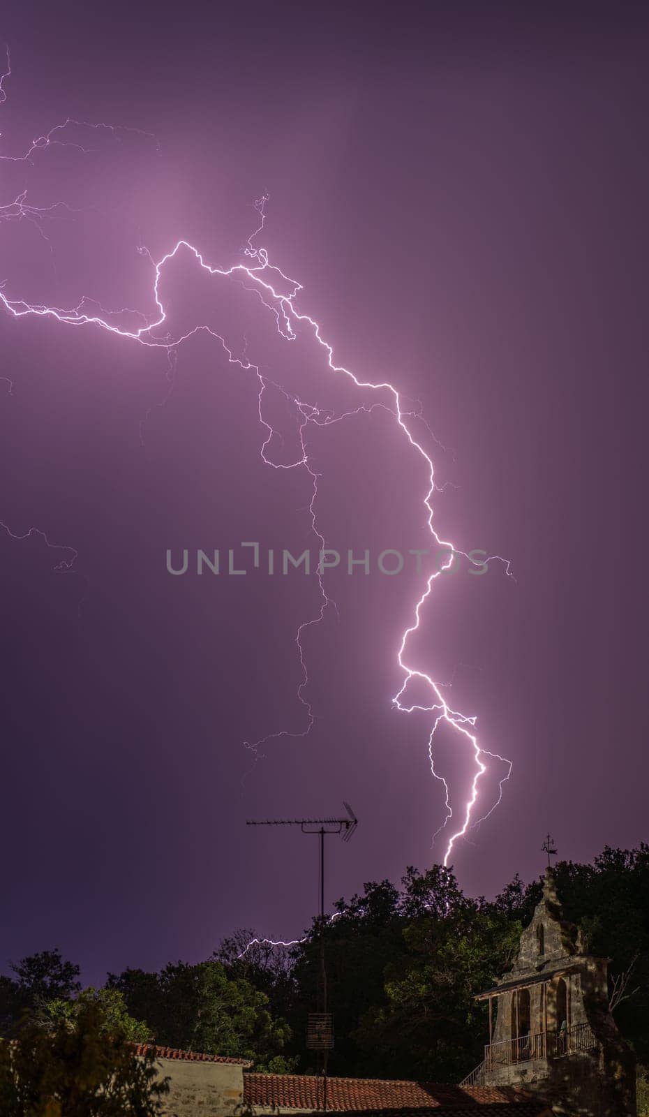 Dramatic lightning brightens night sky over peaceful country chapel.