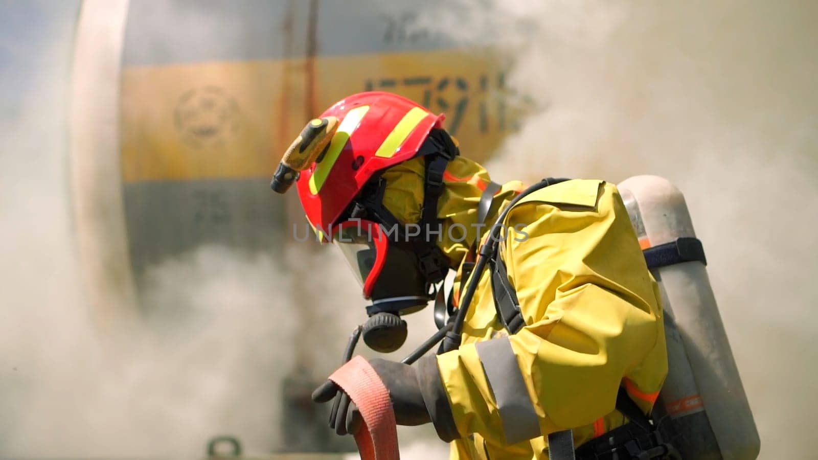 Male firefighter in the helmets and uniform with smoke on the background. Clip. Fireman preparing fire hose, emergency concept