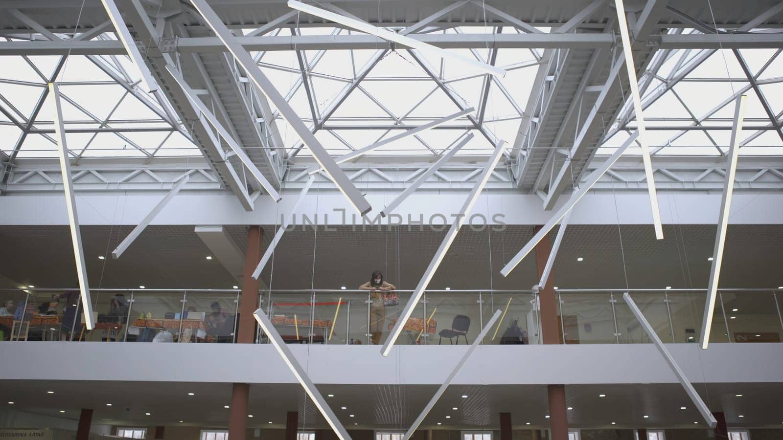 RUSSIA, YEKATERINBURG - MARCH 17, 2022: Glass ceiling and three-story market. ART. The camera looks down. A large light glass ceiling is shown, and under it people walk and buy things.