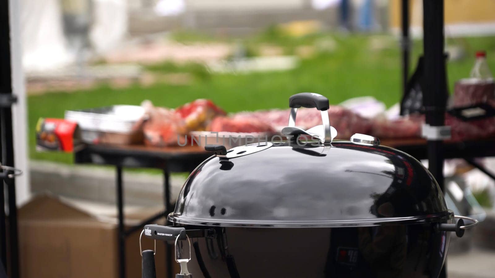 preparing food in a barbecue, outdoors. Closed grill prepares meat in park. Smoke from closed grill.