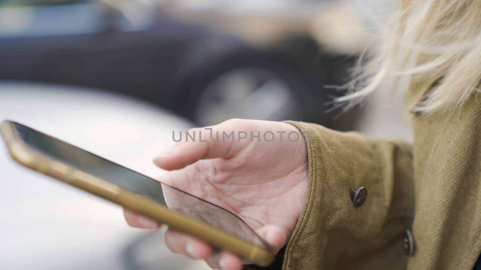 Close-up of woman typing on phone. Media. Woman uses phone on street. Modern touch-sensitive smartphone in hands of young woman.