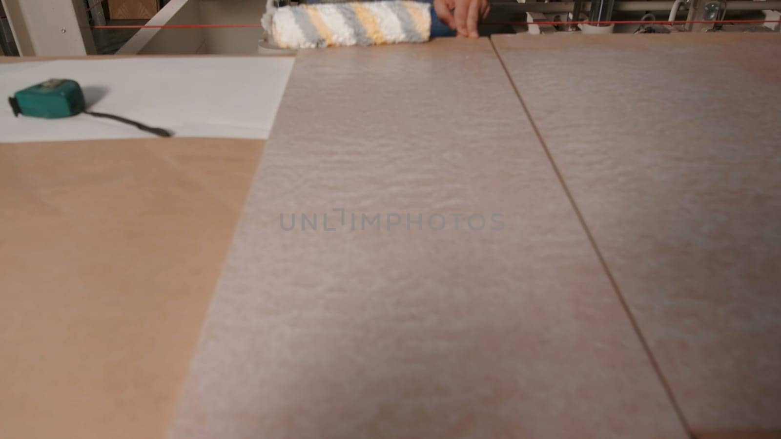 Close up of process of priming wooden board surface at the factory. Industrial background, concept of carpentry