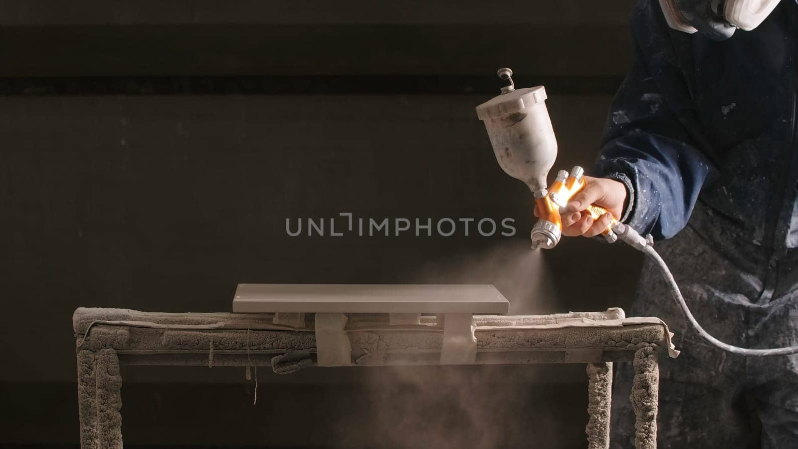 Delhi, India - April 29, 2023: Close-up of man spray painting board in workshop. Creative. Epic painting of board in workshop. Professional spray painting of objects in workshop.