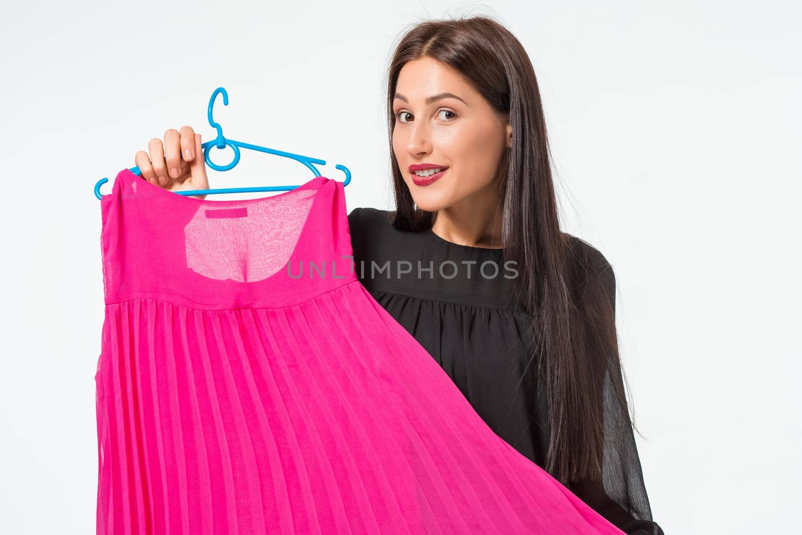 Beautiful young woman choosing dresses on white background