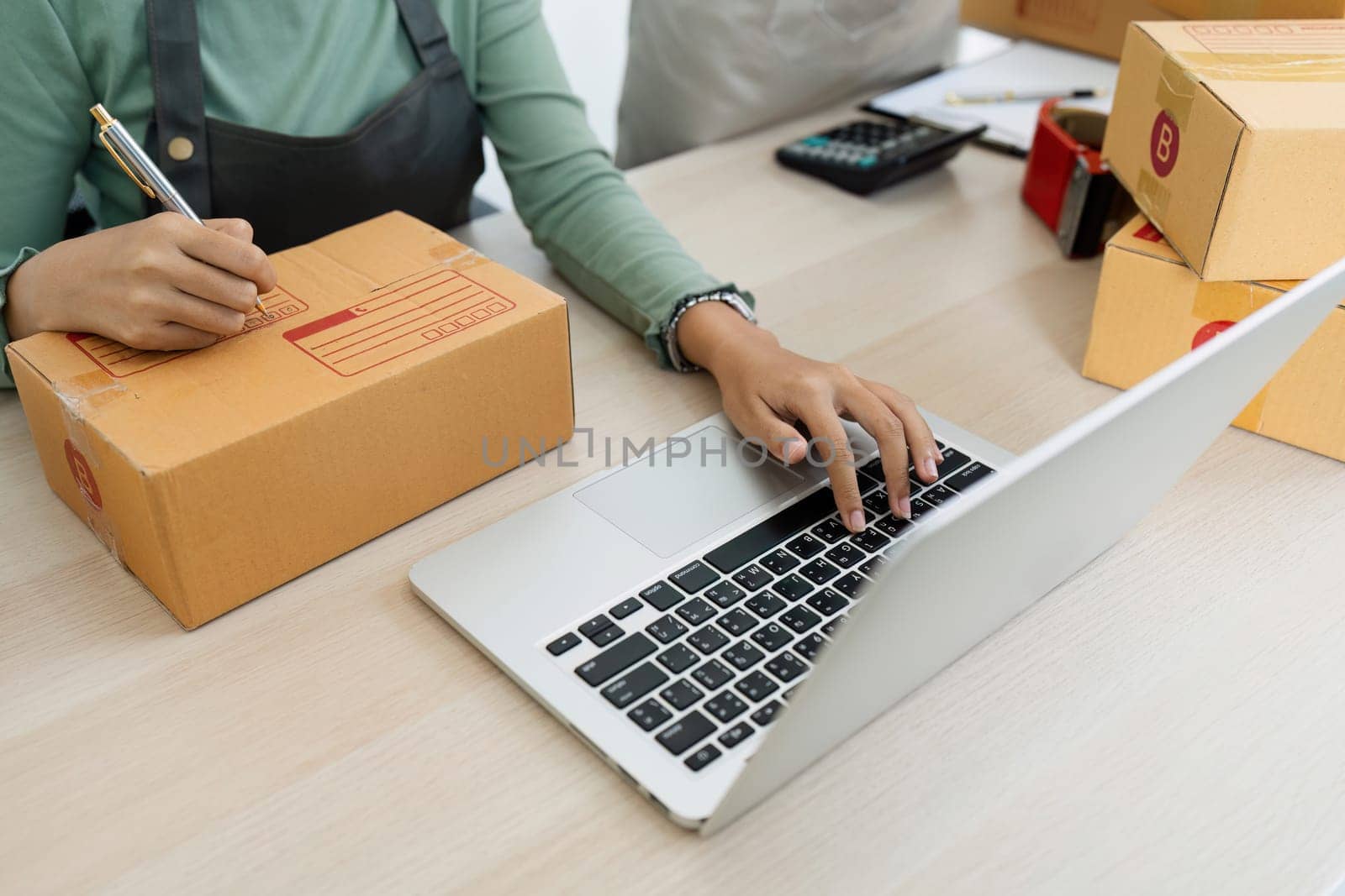 Asian woman using laptop to prepare for delivery to customer. e-business concept by itchaznong