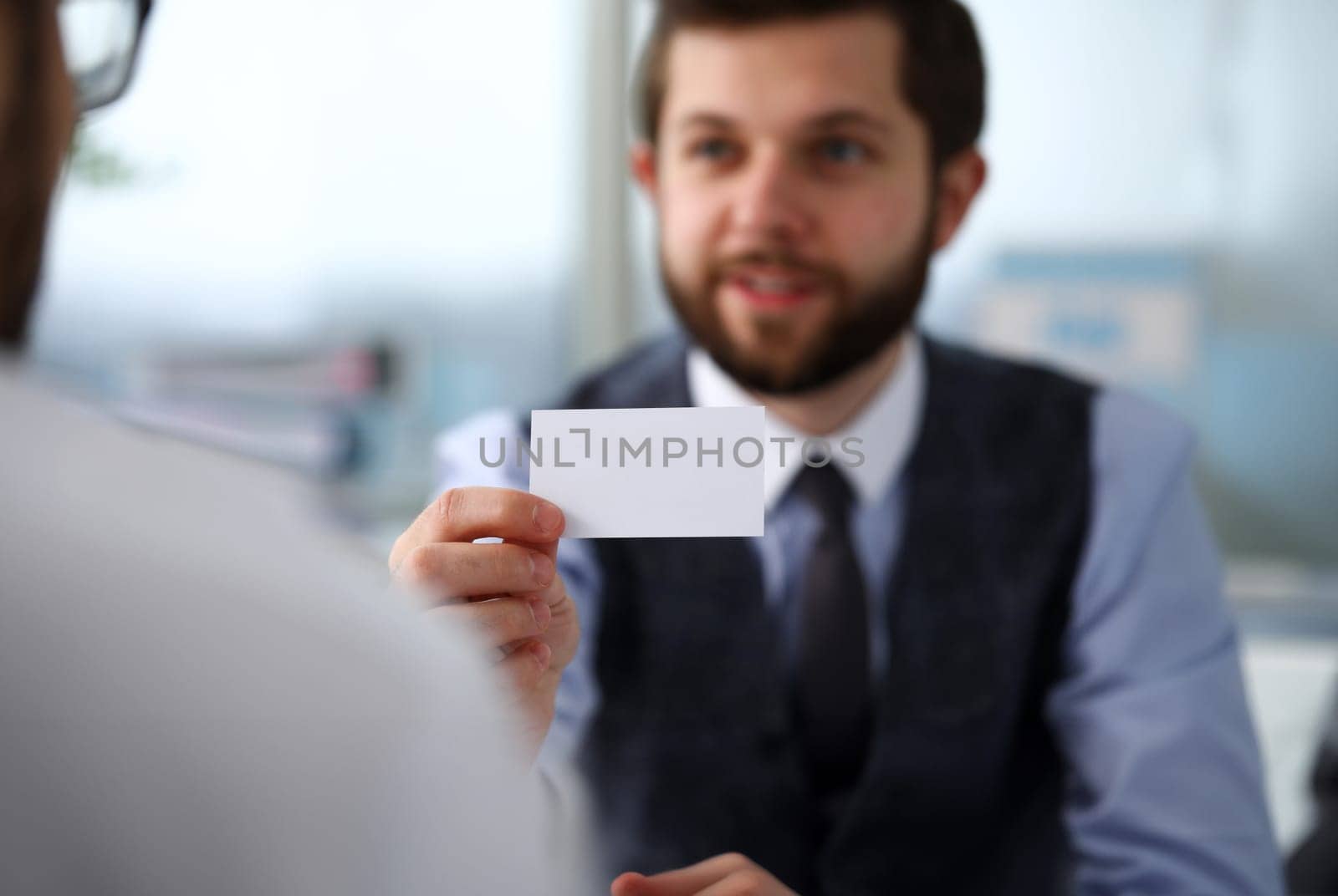 Male arm in suit give blank calling card to visitor by kuprevich