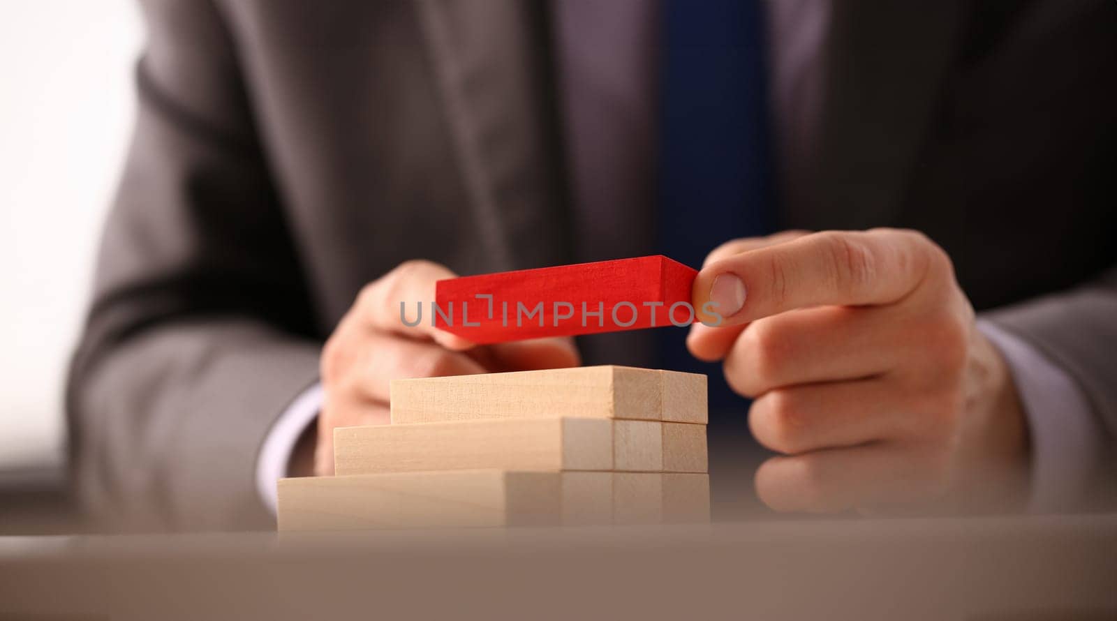 Male hand holds red wood block of stair finish next step rare progress personnel talent authority hot pyramid background on ladder different insurance concept closeup