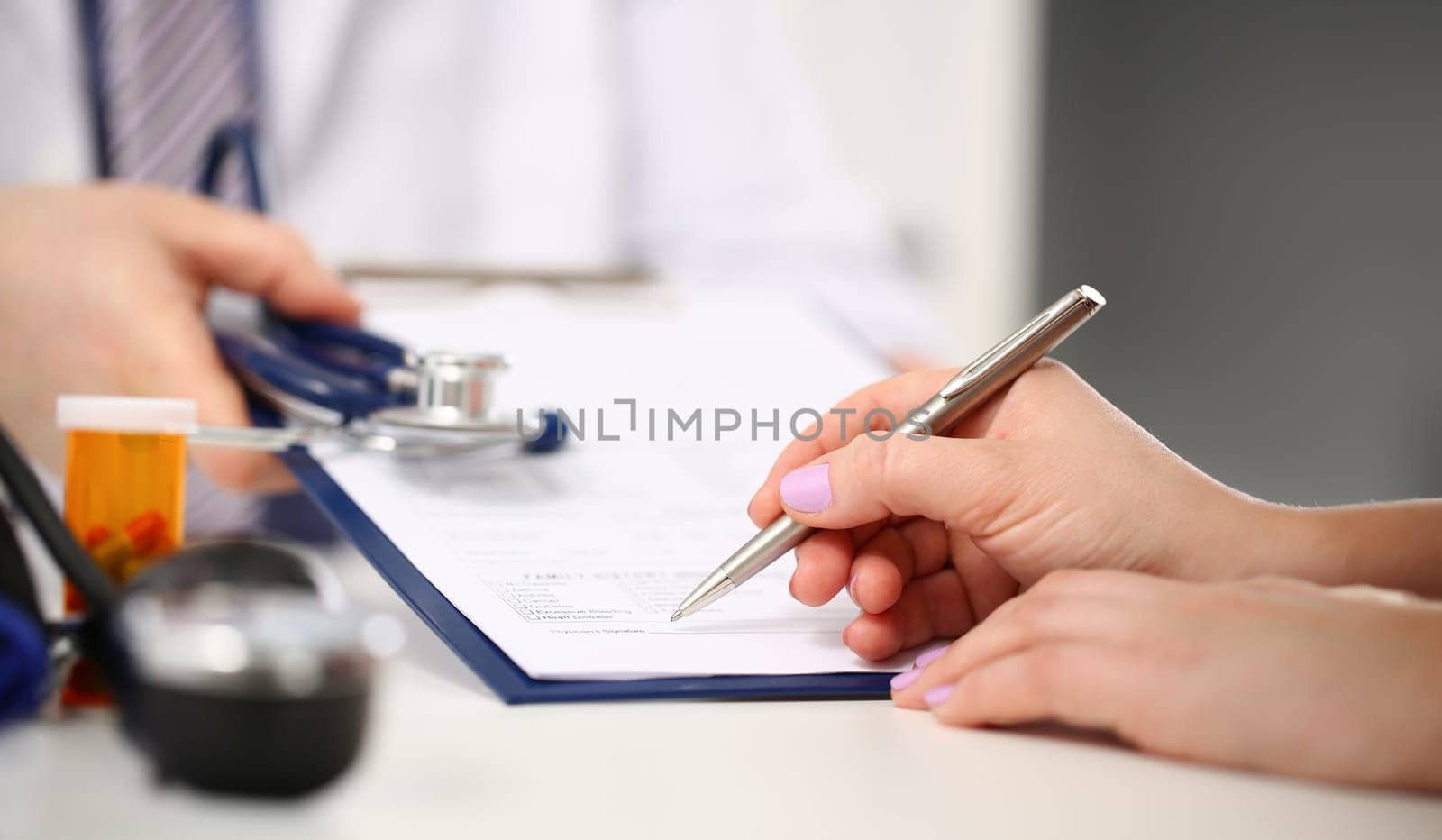 Female doctor hand hold silver pen filling patient history list at clipboard pad. Physical exam er disease prevention ward round visit check 911 prescribe remedy healthy lifestyle concept