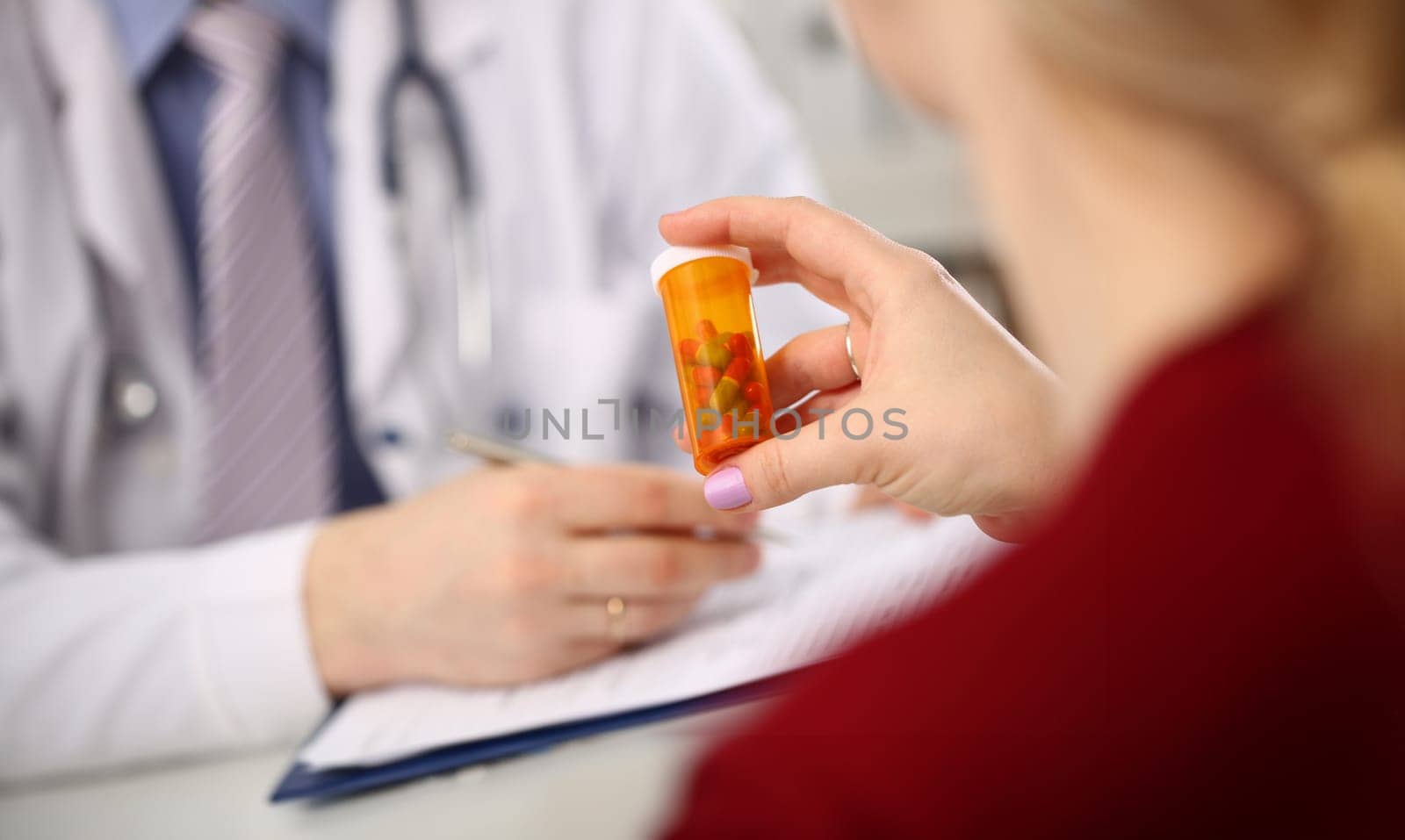 Female medicine doctor hand hold jar of pills and write prescription to patient at worktable. Panacea and life save, prescribing treatment, legal drug store concept. Empty form ready to be used