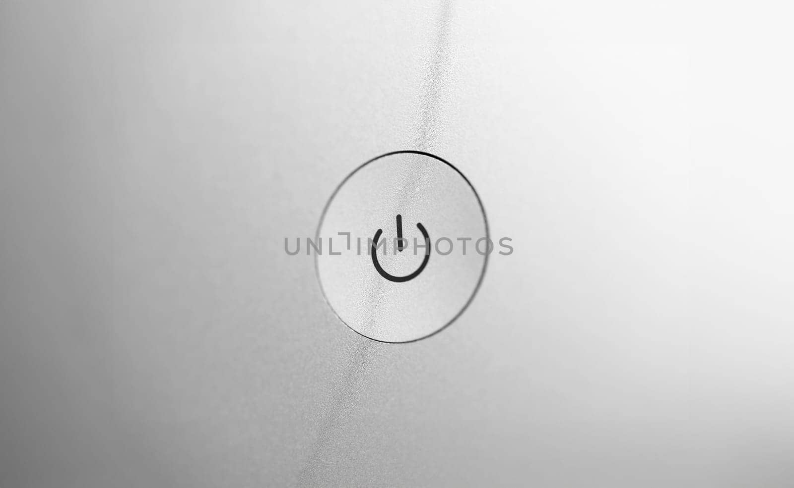 Silver coarse turn on and off button at gray blank back panel of electronic gadget closeup