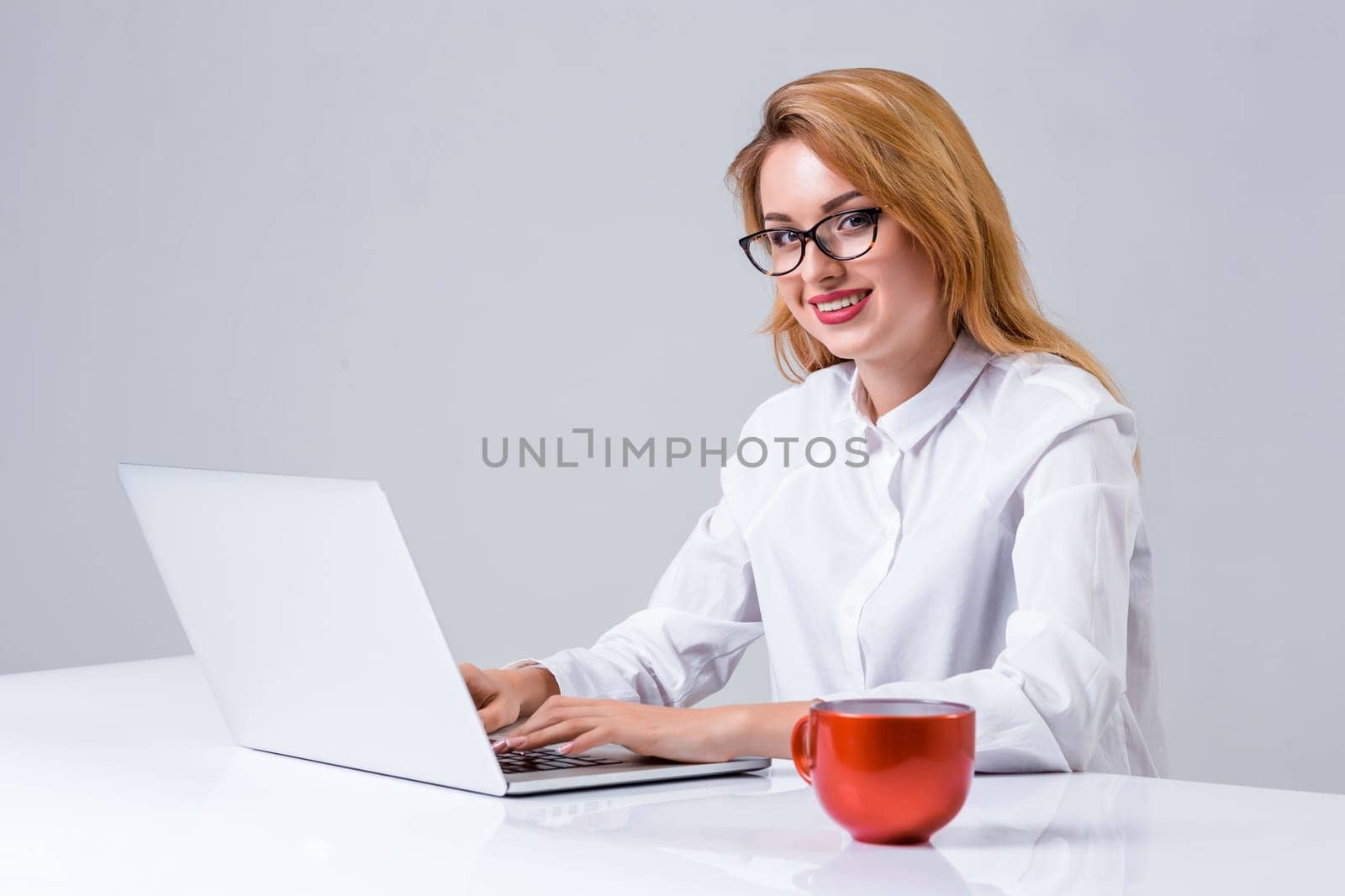 Young businesswoman working at laptop computer. she smiles, prints and looking at monitor