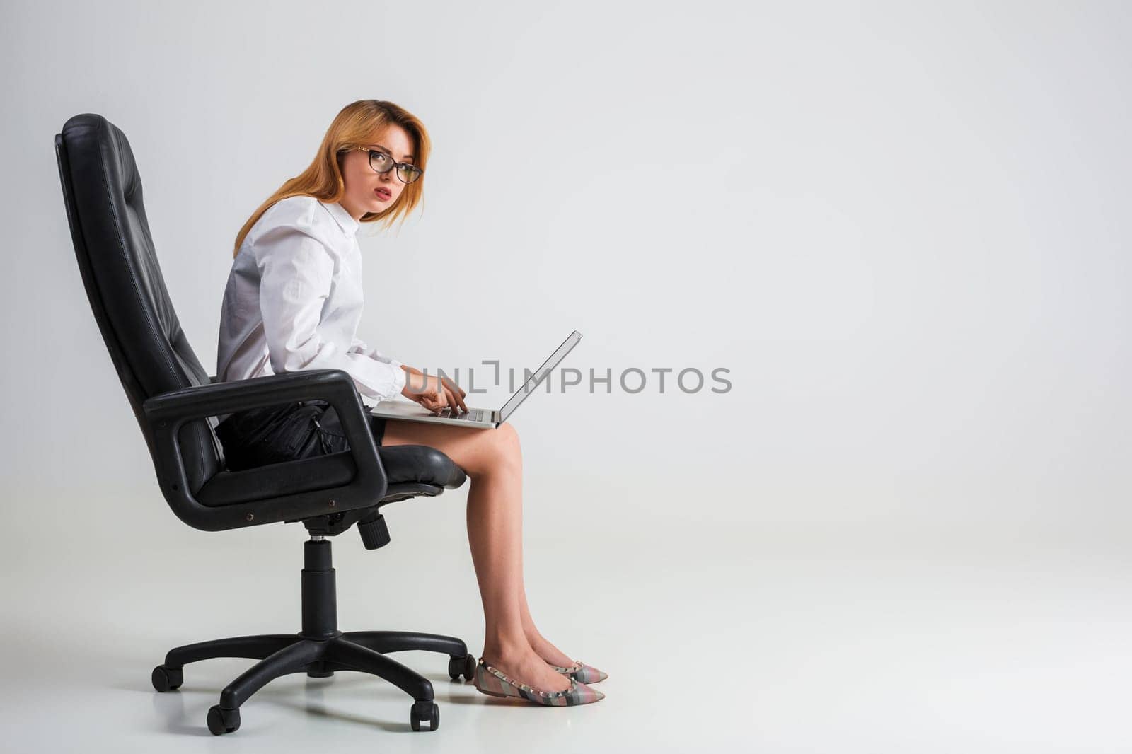 young woman sitting on the chair and using laptop. tired businesswoman under the weight of hard work. hunchbacked