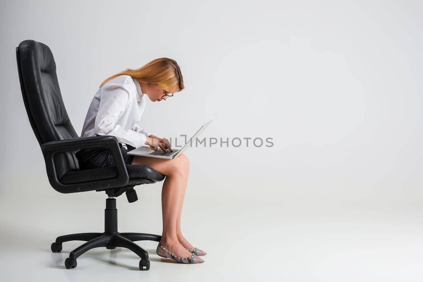 young woman sitting on the chair and using laptop. tired businesswoman under the weight of hard work. hunchbacked