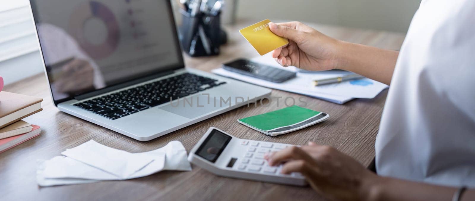 Woman holding credit card payment internet banking or shopping concept. calculating tax or payment. laptop, credit card, calculator on desk.