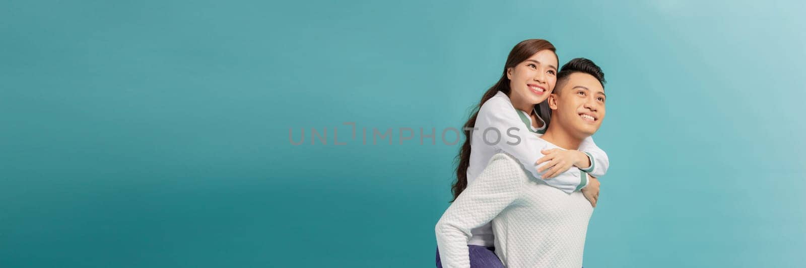 Cute couple embracing and looking the camera on light blue background by makidotvn