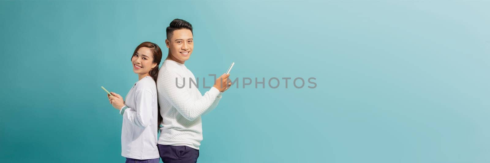 image of asian couple holding smartphone, isolated on blue background