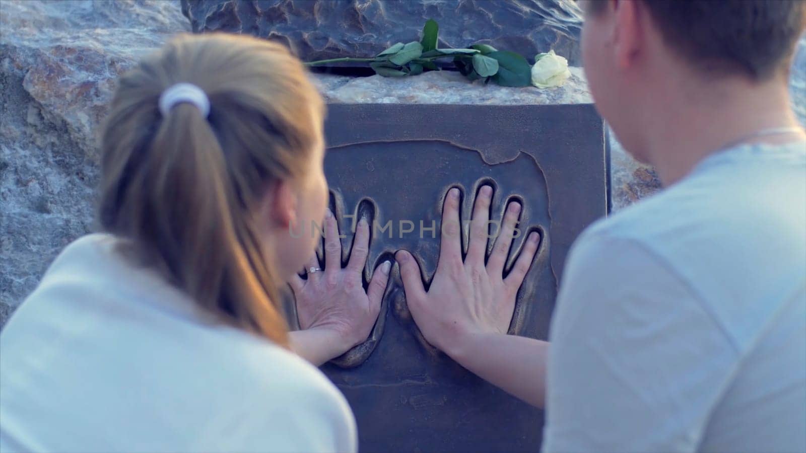 The couple puts hands to the monument couple in love on date stands at the monument. to attach the arm to the monumentHD