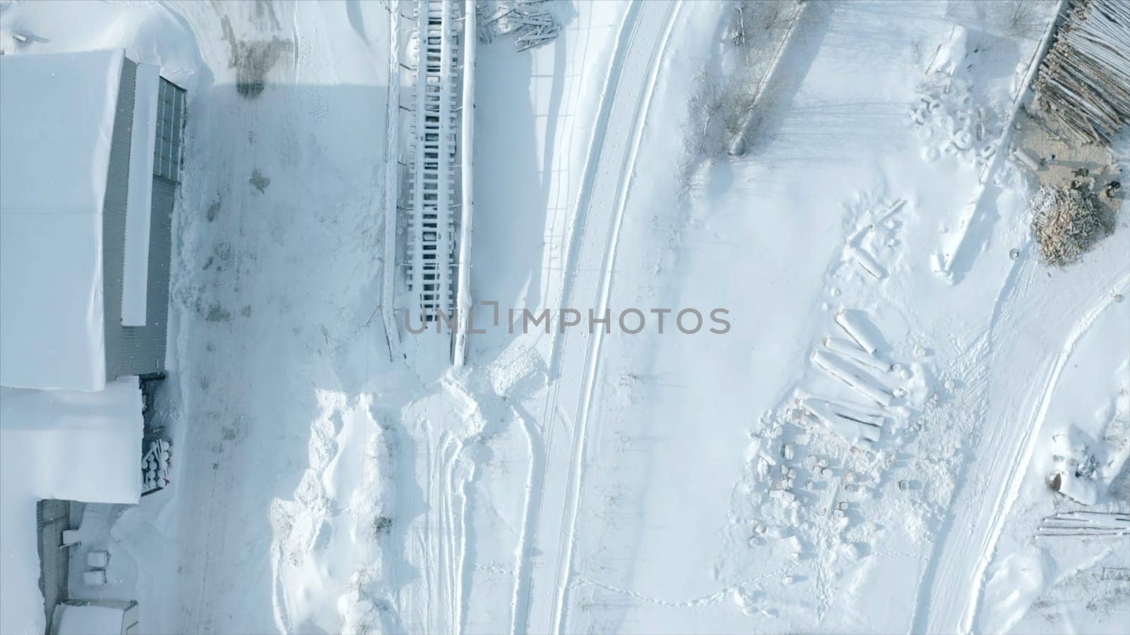 Top view of railway with snow. Clip. Empty snow-covered railway rails in winter. Snow falling on sunny day on railway.