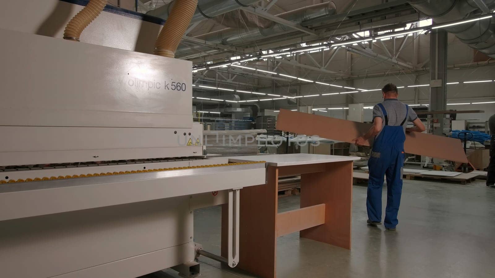 Delhi, India - April 29, 2023: Work in a factory. Stock footage. Workaholics in special clothes make furniture and boards with the help of special advanced machines. High quality 4k footage