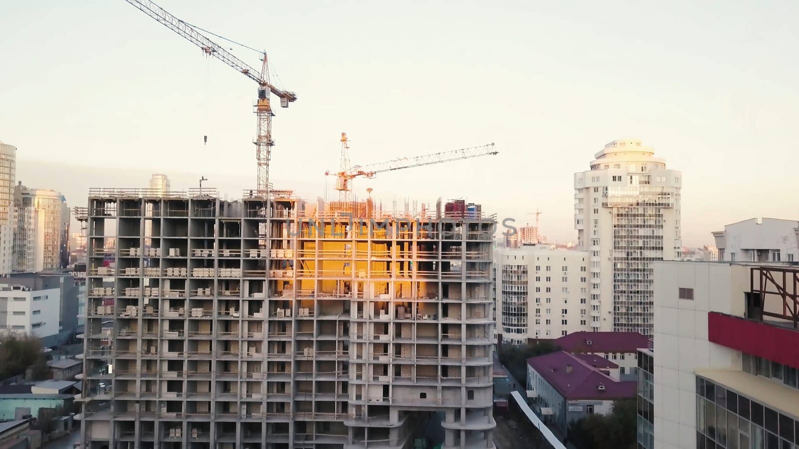Construction site with cranes. Video. Construction workers are building. Aerial view. Top view of the construction site in the city. Construction in the city with a crane manipulator.
