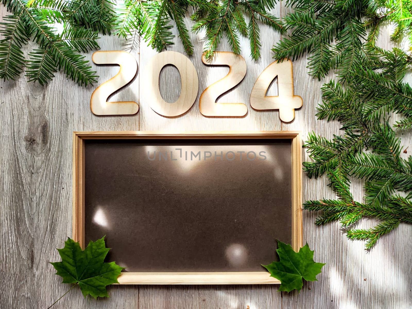 Wooden figures and numbers of the new year 2024 with frame and fir branches of Christmas tree. Celebration. Abstract background, pattern, frame, place for text, copy space