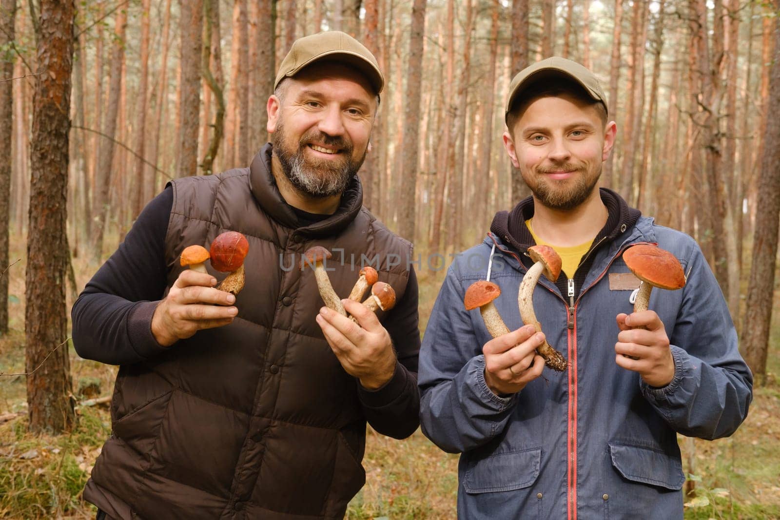 Two mushroom pickers in the forest are holding aspen trees in their hands. Mushrooms in the forest. Mushroom picking by Lobachad
