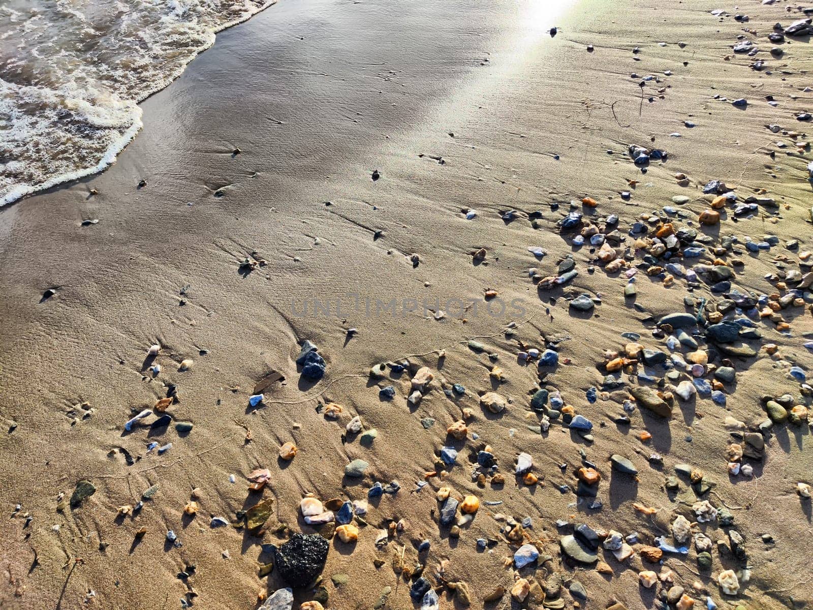 Yellow sand, pebbles and a transparent wave as a background, texture. Abstract pattern, place for text and copy space