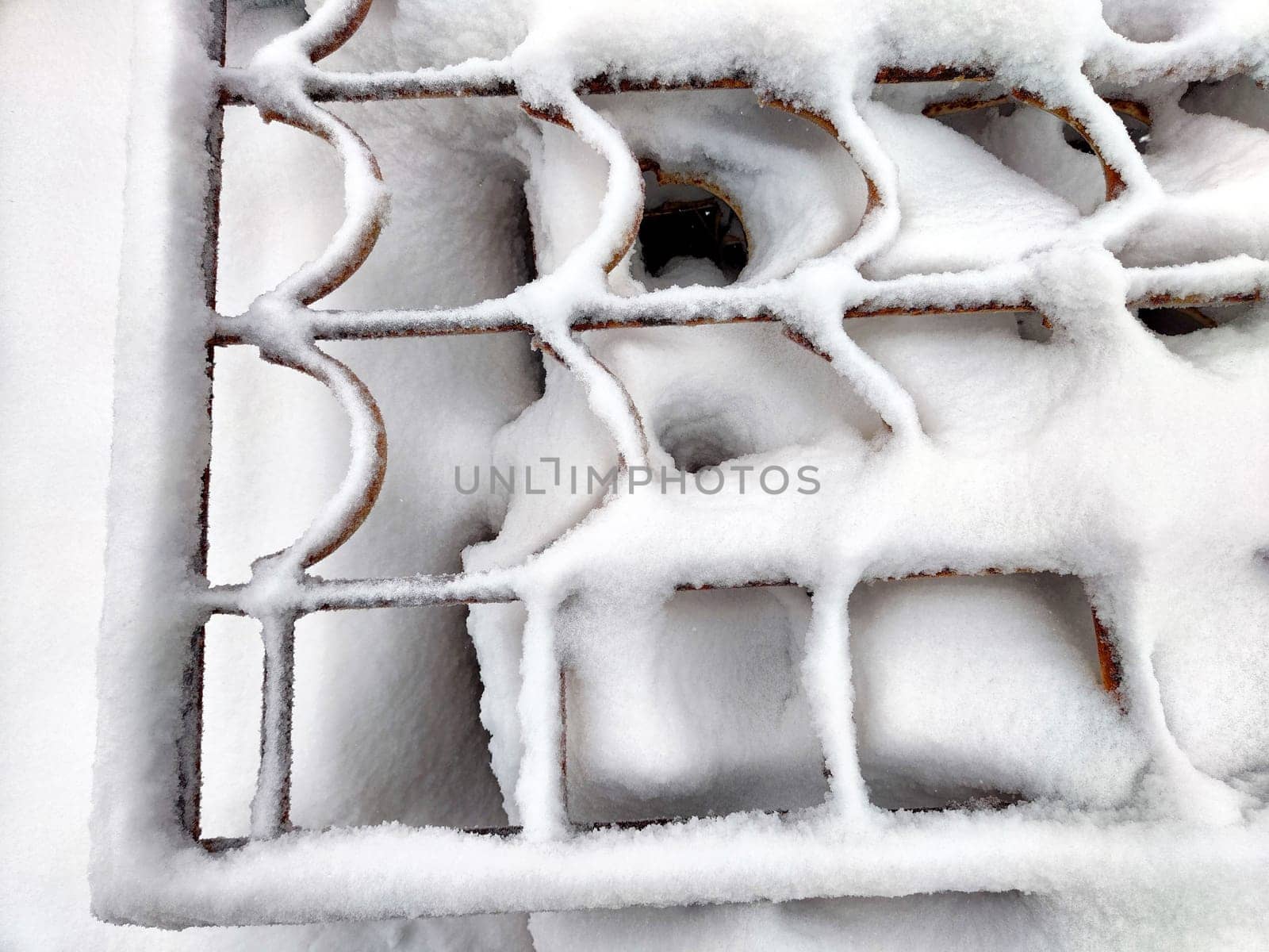 Wrought iron curly wavy lattice in the snow in winter. Abstract background, pattern, frame, texture, place for text and copy space by keleny