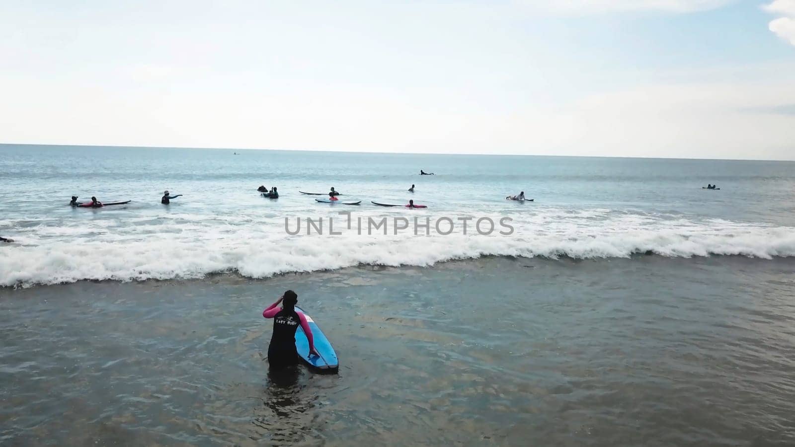 Surfing girl on surfboard on sunrise in the ocean. People ride good wave. Modern active sport lifestyle and summer vacation. People riding boards on the waves.