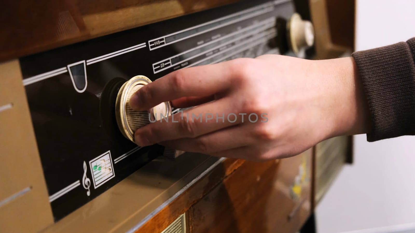 Close-up of man's hand rotating the knob on the old radio. Vintage technology