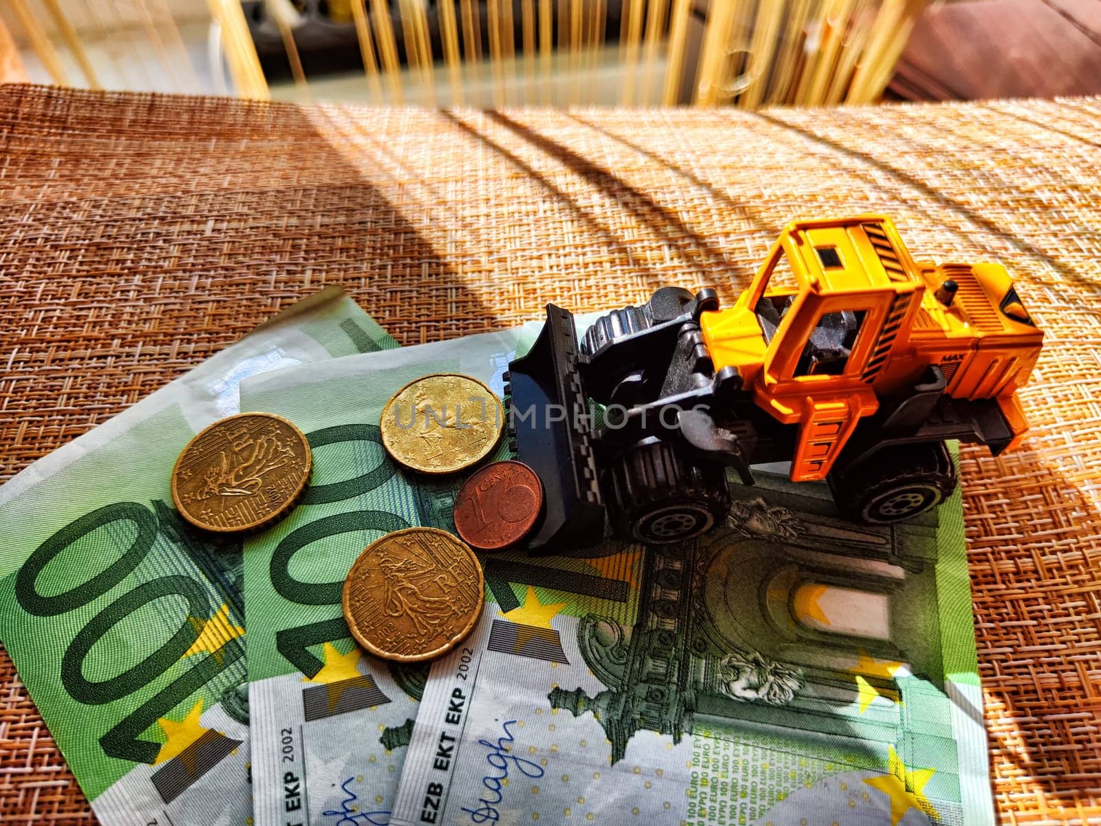 A small toy tractor or excavator on bundle of money. The concept of the high cost of technology. The possibility of earning money with construction machinery