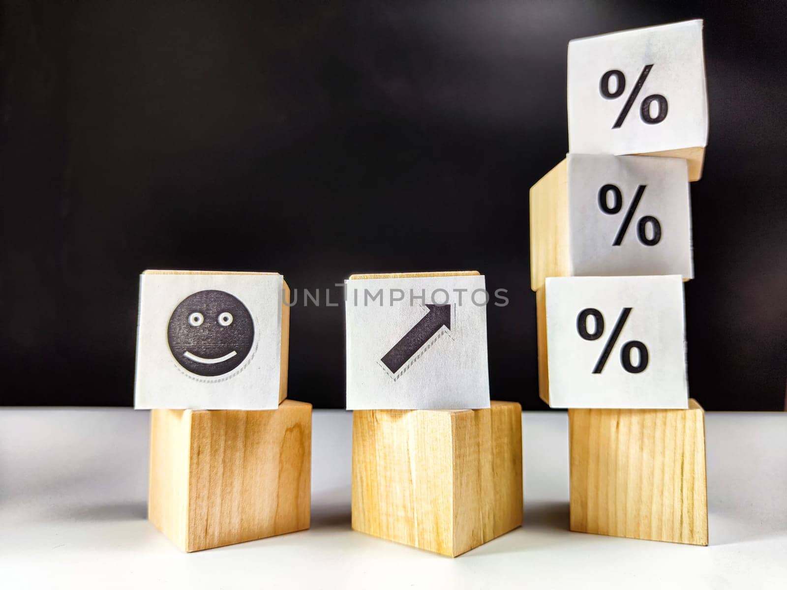 Wooden cubes in a column and row with white signs with a smiley sign, an arrow, a percentage. The concept of positivism. Positive thinking leads to the achievement of results and profits