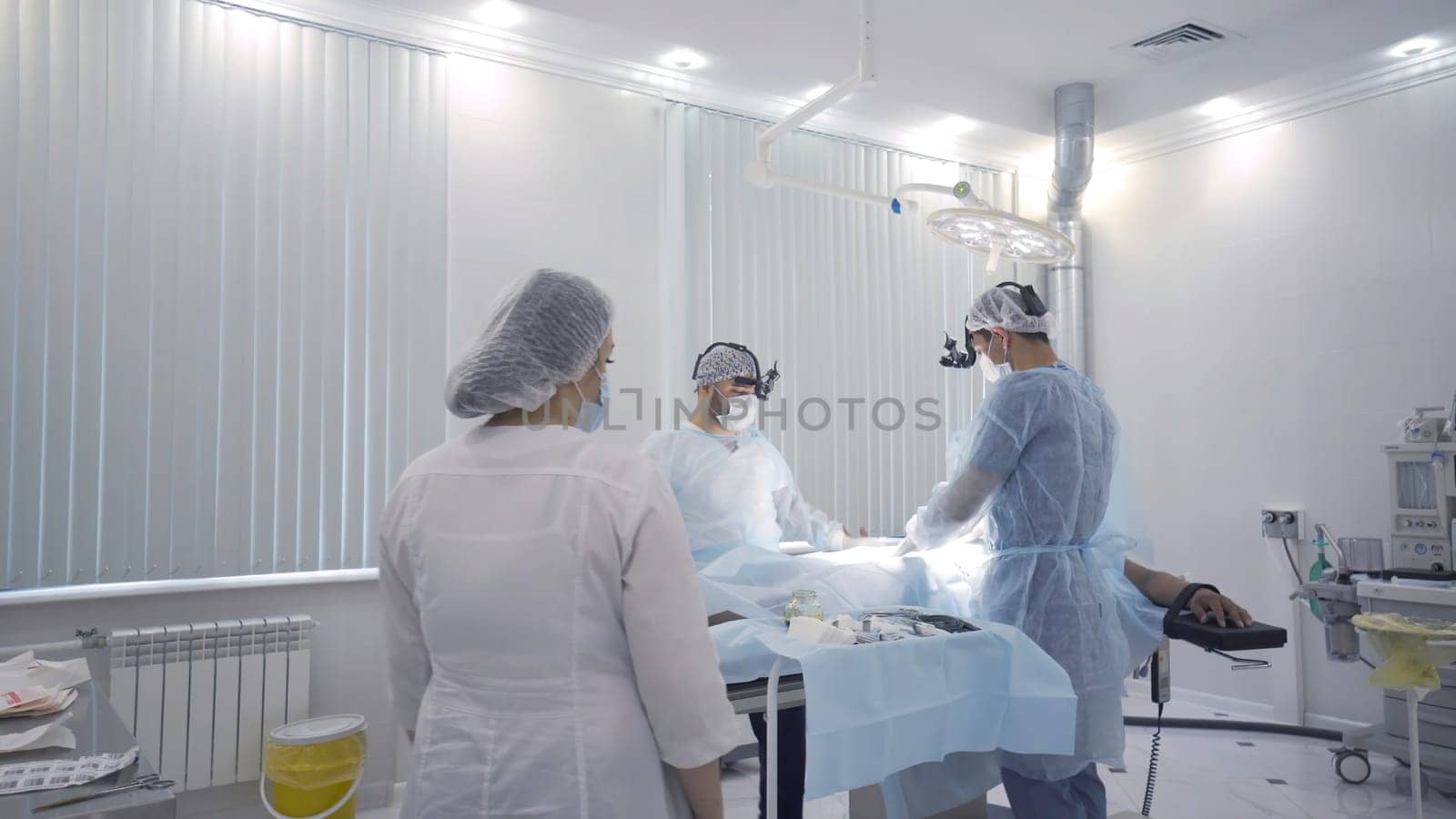 Professional doctors and nurse prepare patient for surgery. Action. Preparing patient for surgery and anesthesia in modern light operating room. Surgical treatment.