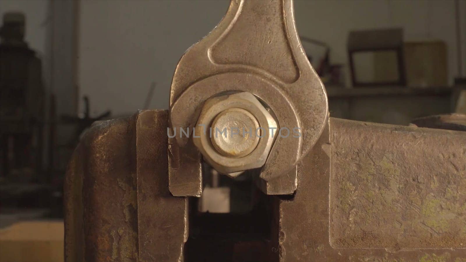 Iron Wrench in hand unscrews the large hex bolt. Wrench is tightening the chrome nut on the blue metal folding shelf. Iron Wrench in hand unscrews the large hex bolt. The wrench steel tools for repair. Detail of chrome wrench turning a nut on a bolt