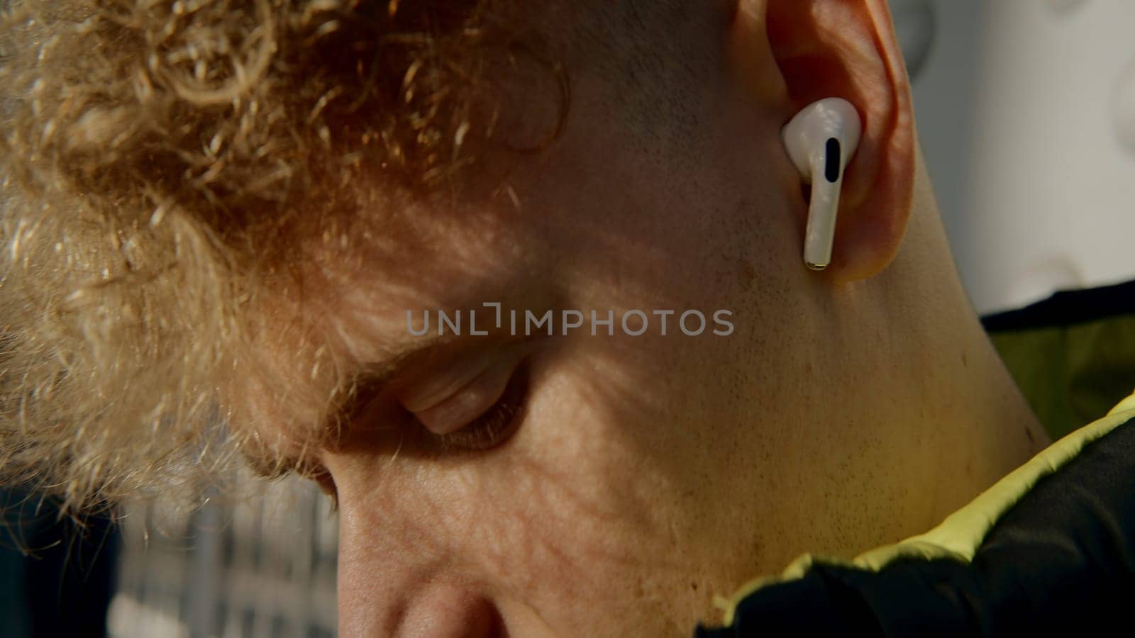 Close-up of young man singing along to music with headphones. Action. Young man in wireless headphones on street. Young man listens to music and sings along.
