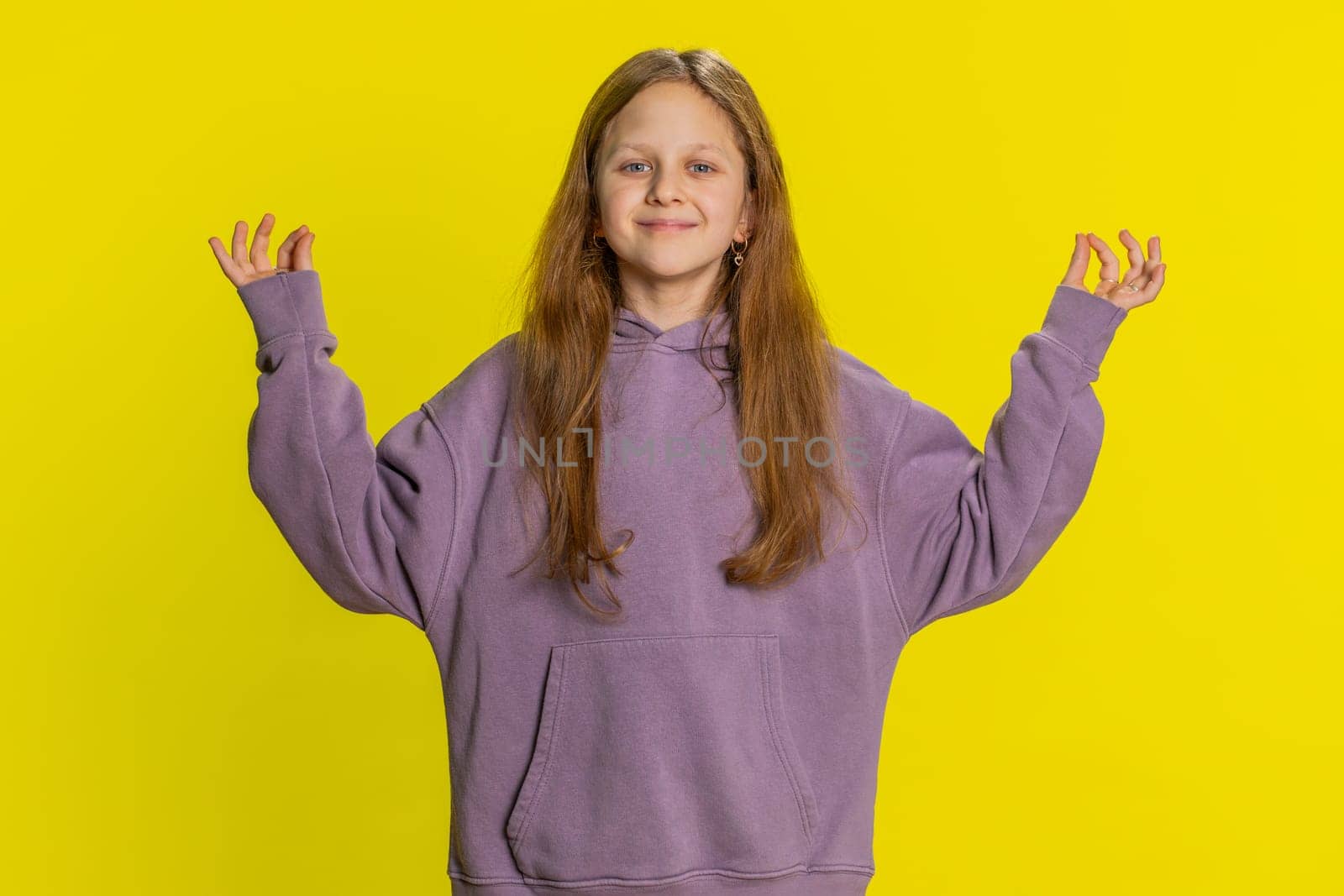 Keep calm down, relax rest. Concentrated happy smiling preteen child girl kid meditating breathes deeply with mudra yoga gesture eyes closed peaceful mind taking a break. Children on yellow background
