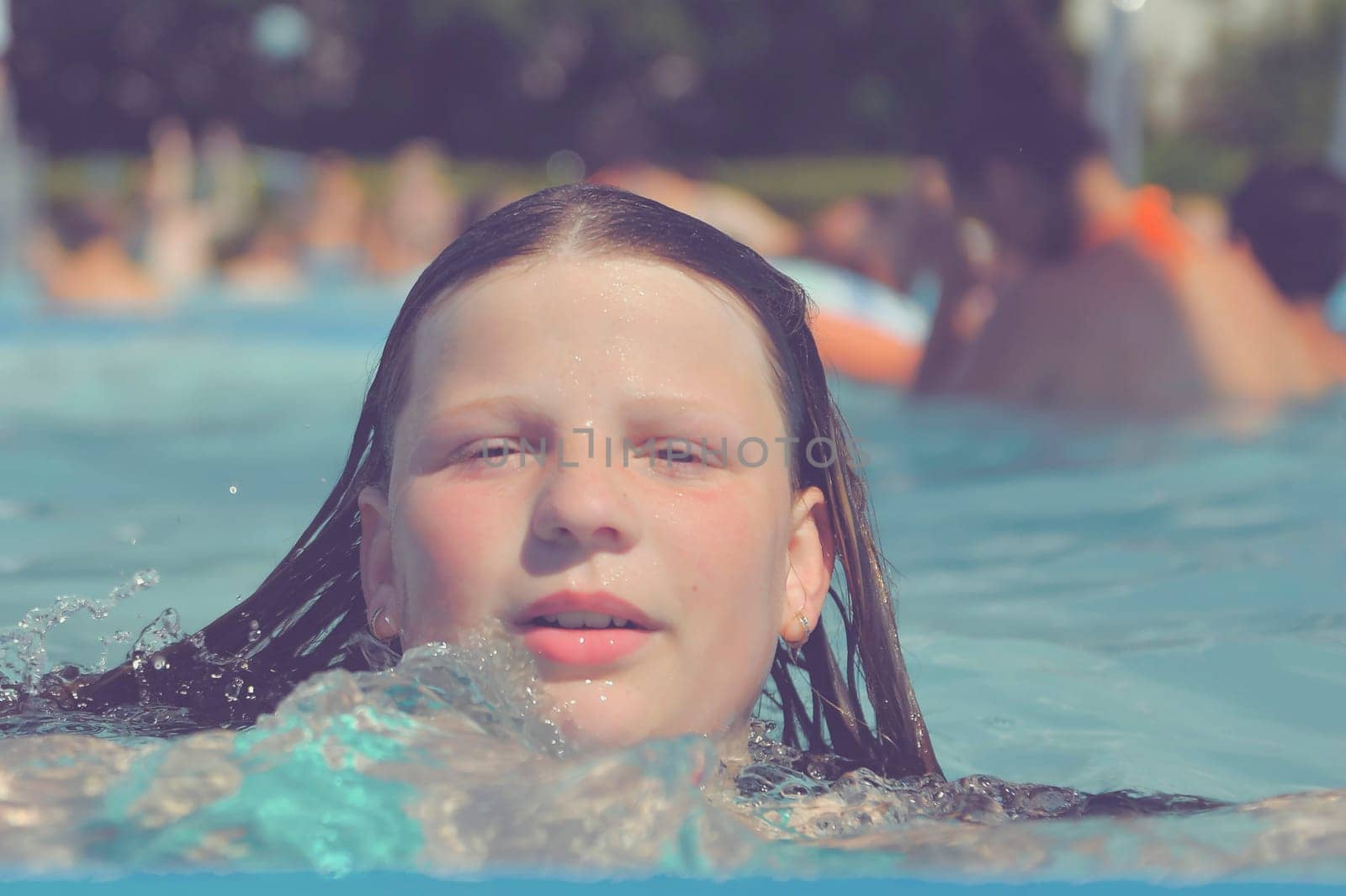 A picture of a little girl at a swimming pool in summer. A small girl swimming to the edge of a swimming pool at a swimming pool. Concept of summer, water fun, sun and relaxation by roman_nerud