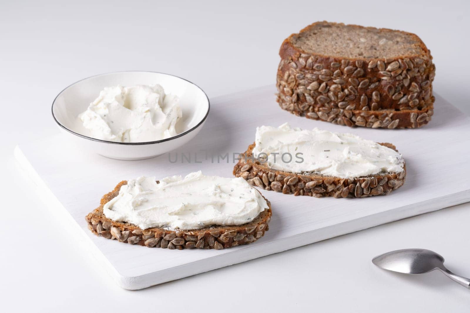 Rye bread with cream cheese on white table. Whole grain rye bread with seeds.