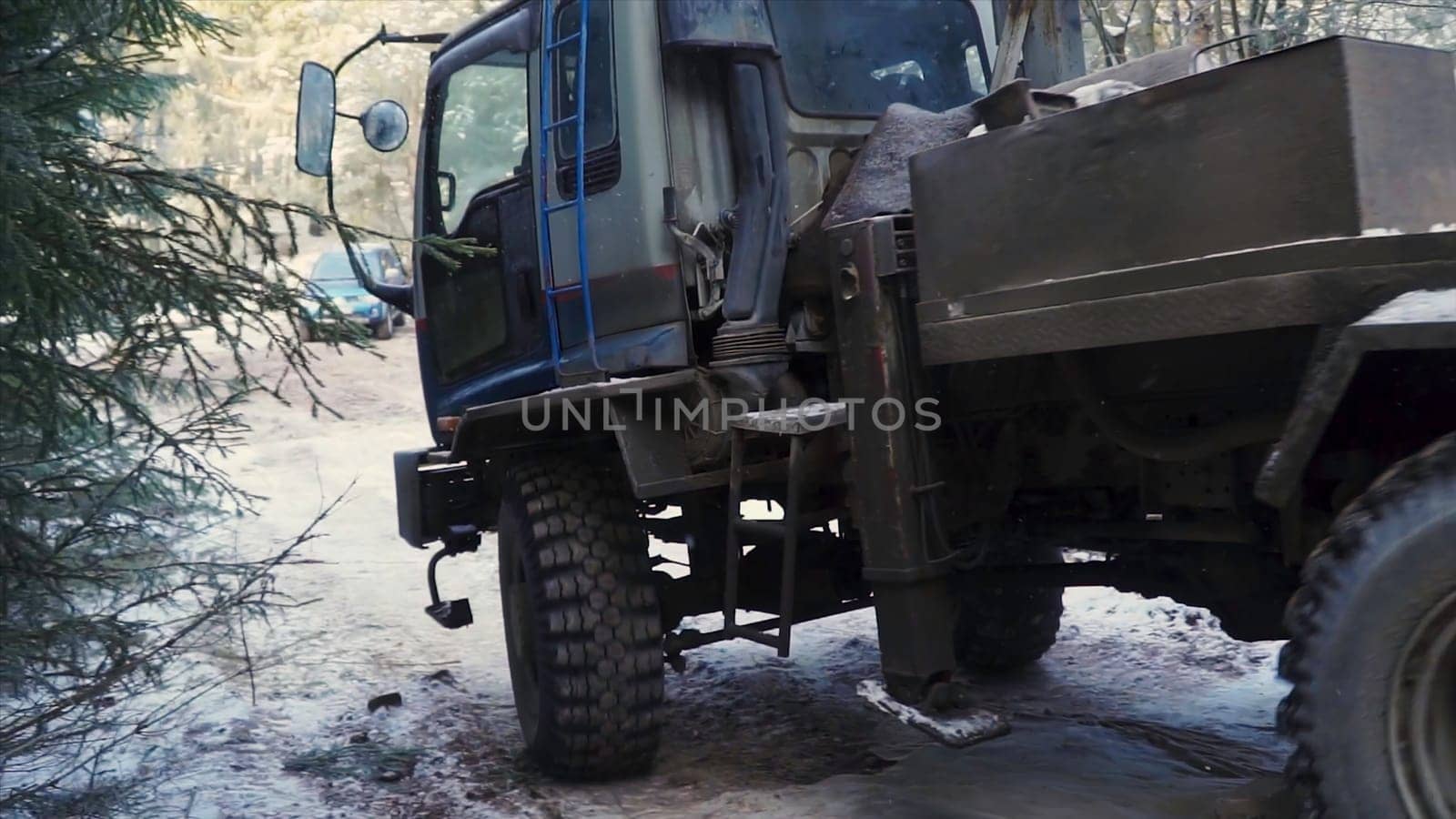Industrial truck rides in winter forest. Clip. Truck drives along forest road with snow. Truck with crane or machinery is traveling in forest part.