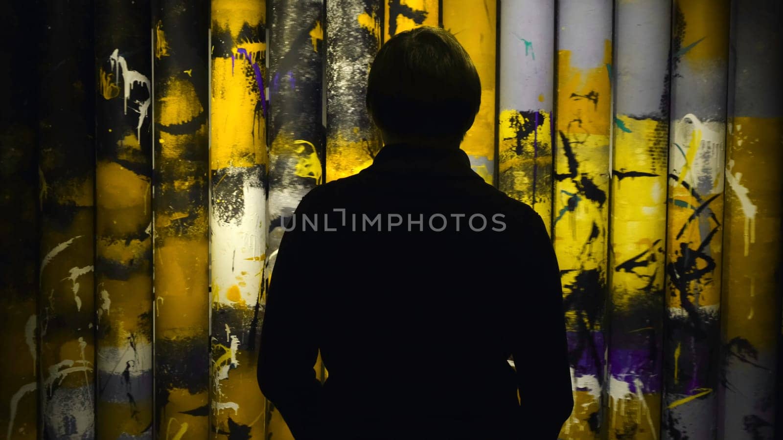 View from the back of man looking at the colorful paintings rotating on the rolls in the museum of Modern Art. Gallery in Saint Petersburg