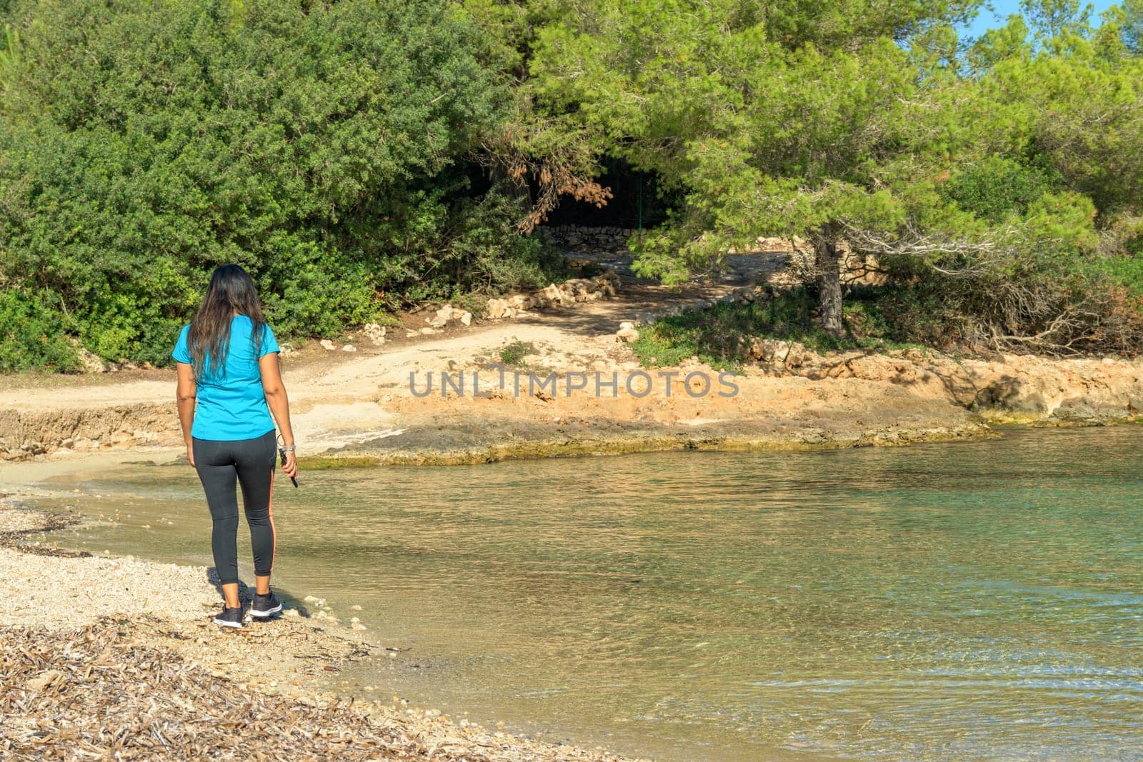 latina woman in sportswear walking along the beach,