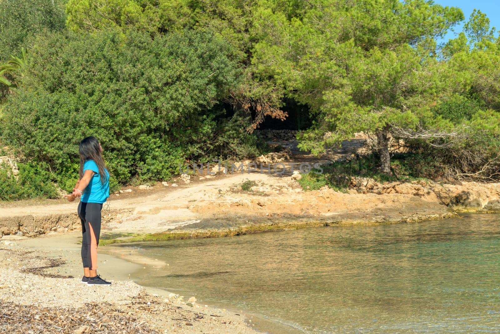 latina woman, on the shore of the beach looking at the sea breathing deeply,