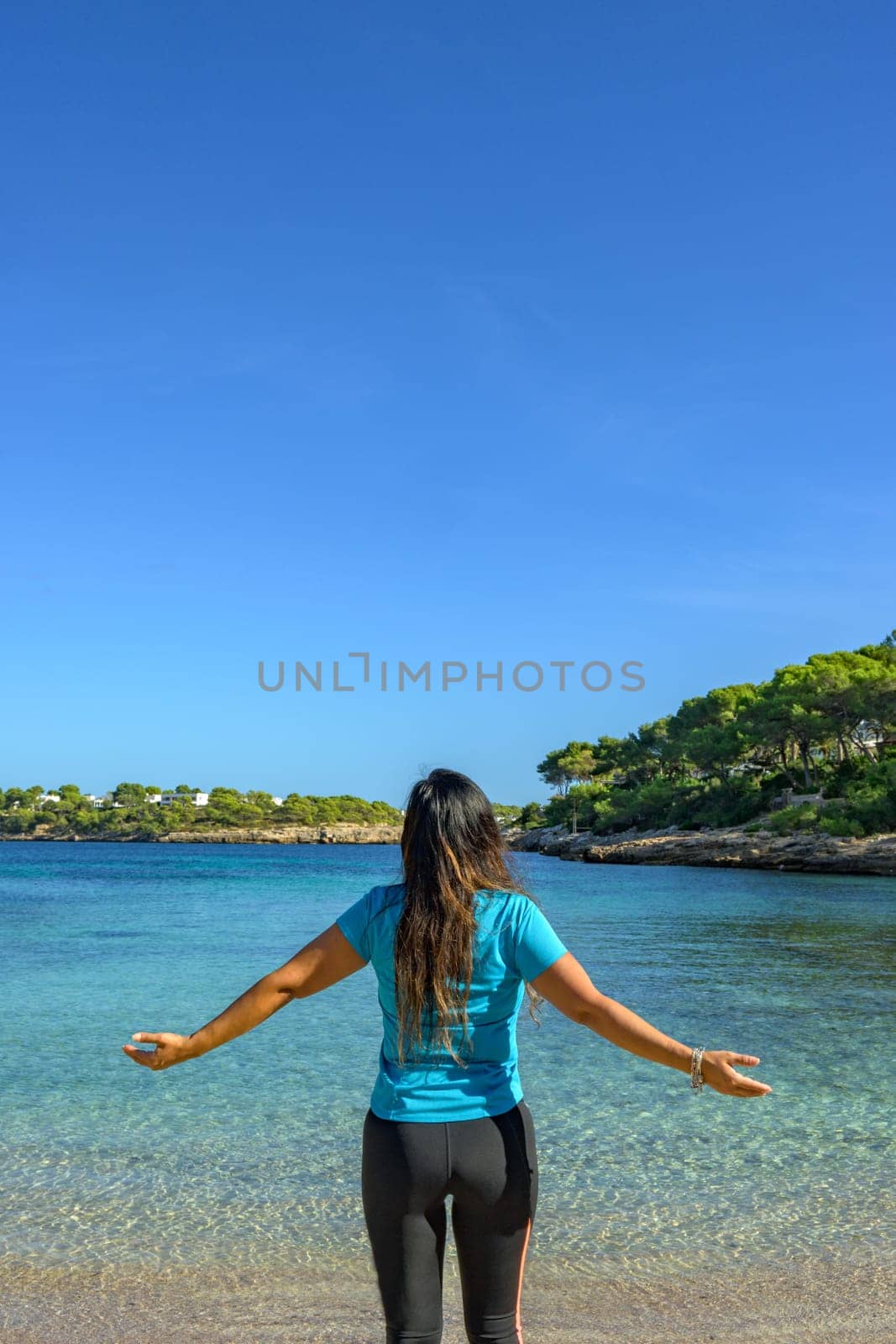 Latina woman, seen from behind, in sportswear, looking at the sea, breathing deeply.,