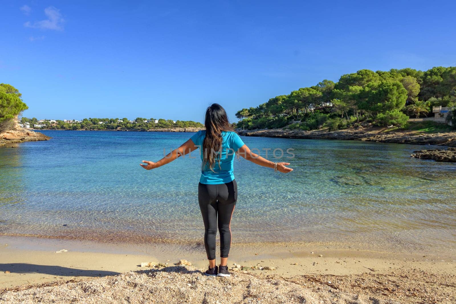 latina woman, in sportswear on her back, on the shore of the beach looking at the sea breathing deeply.,